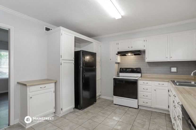 a kitchen with white cabinets and a black refrigerator