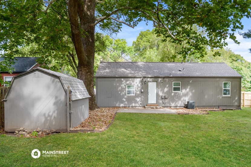 a galvanized shed and a garage in a backyard with a tree