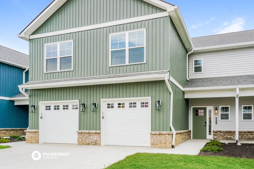 a green house with two white garage doors