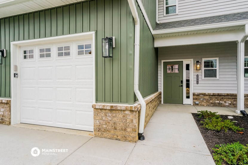 a green and white house with two garage doors