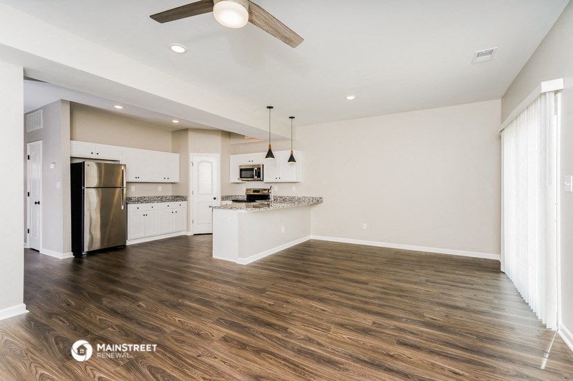 an open kitchen and living room with wood flooring and stainless steel appliances