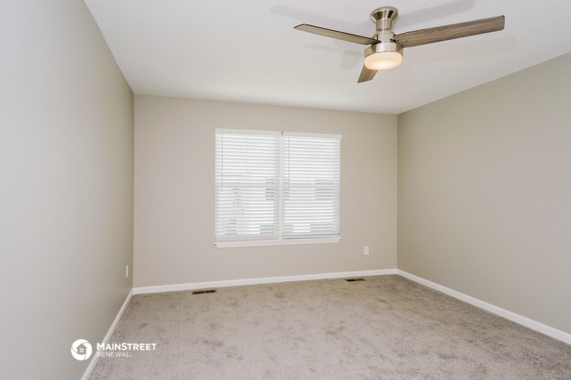 an empty room with a ceiling fan and a window