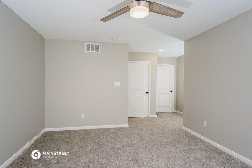 a empty living room with a ceiling fan and a white door