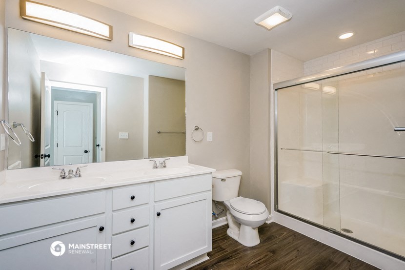 a white bathroom with a large mirror and a shower and a toilet