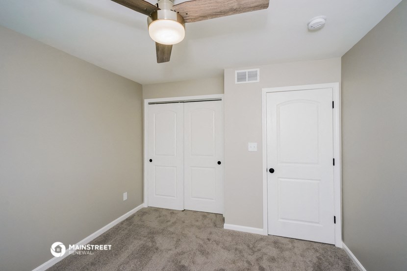 a bedroom with two closets and a ceiling fan