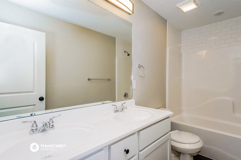 a bathroom with a large mirror and a sink and a toilet