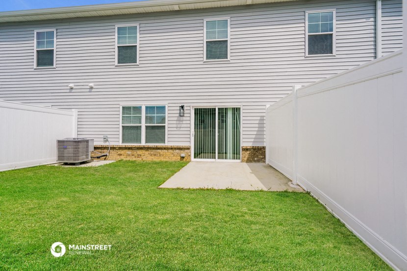 a side view of a white house with a yard and a backdoor