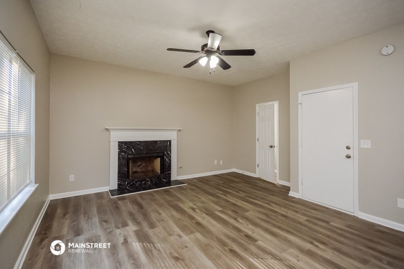 the spacious living room with fireplace and ceiling fan