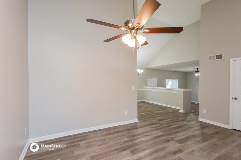 the living room of an apartment with a ceiling fan