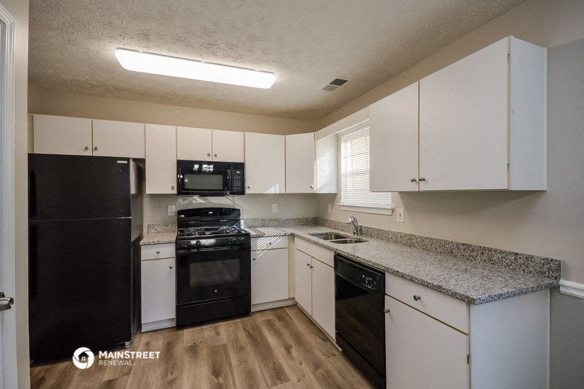 a kitchen with white cabinets and black appliances and granite counter tops