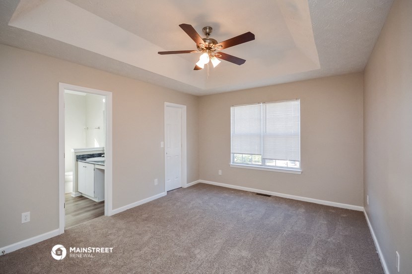 the spacious living room with ceiling fan and carpet