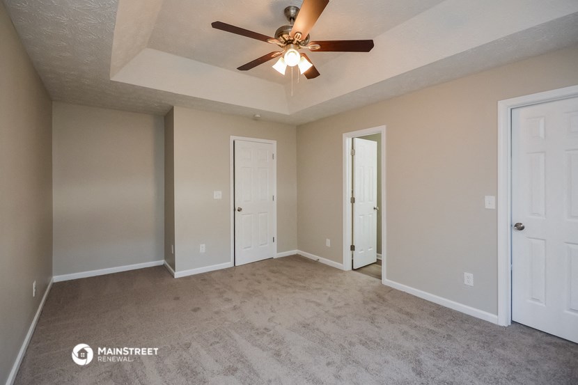 the spacious living room with ceiling fan and carpeting