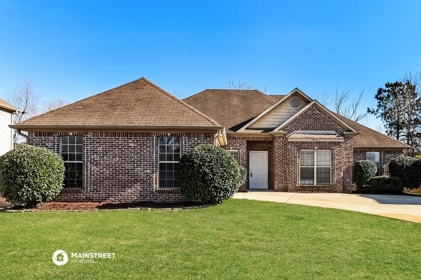 a brick house with a green lawn and a blue sky