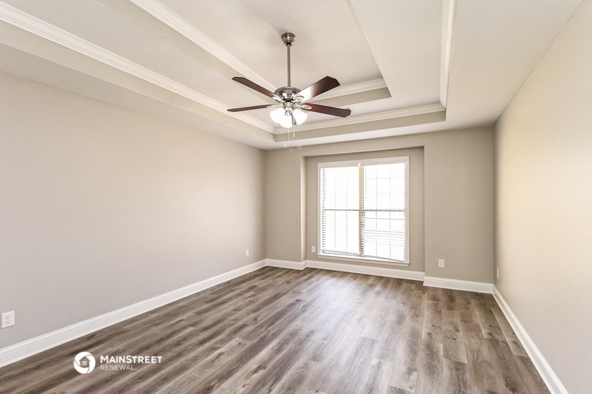 an empty living room with a ceiling fan and a window