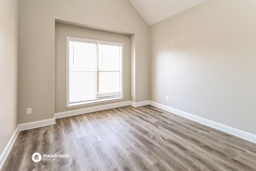 an empty living room with wood floors and a window
