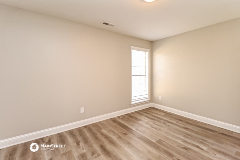 an empty living room with wood flooring and a window