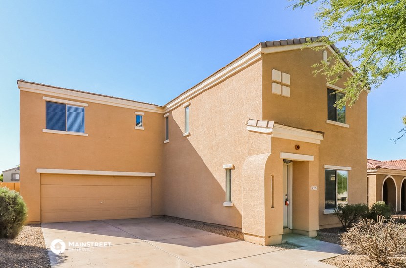 a tan house with a garage door and a tree