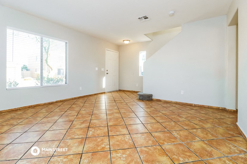 an empty living room with tile flooring and a window