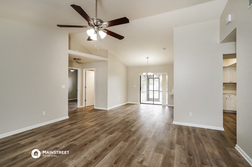 the living room and dining room of an empty house with a ceiling fan