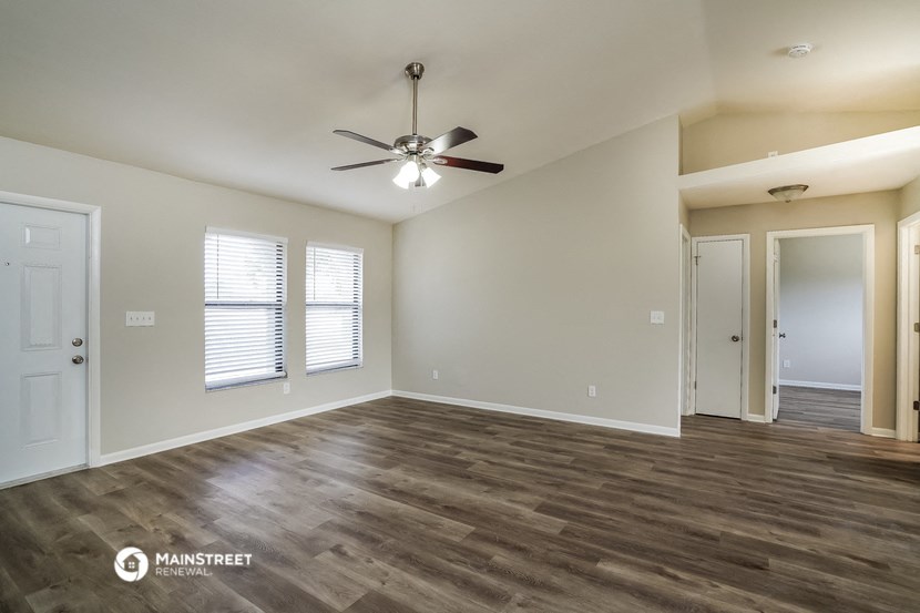 the living room of an empty house with a ceiling fan