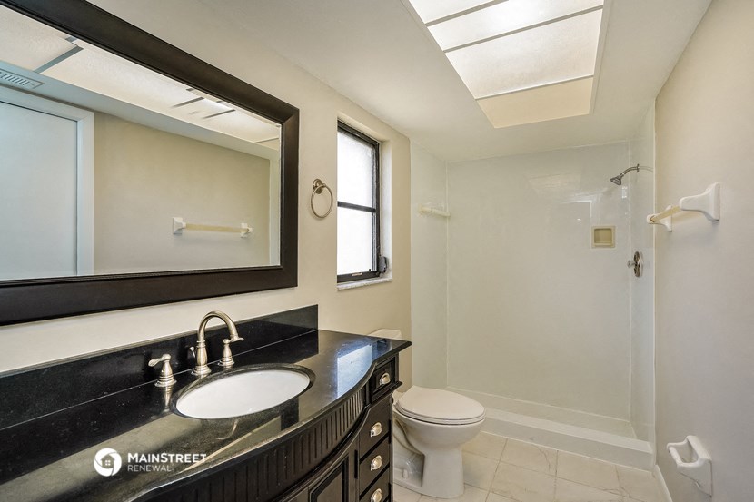a bathroom with a large mirror and a sink and a toilet