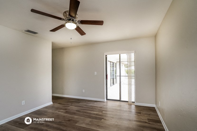 the spacious living room with ceiling fan and sliding glass door to the patio