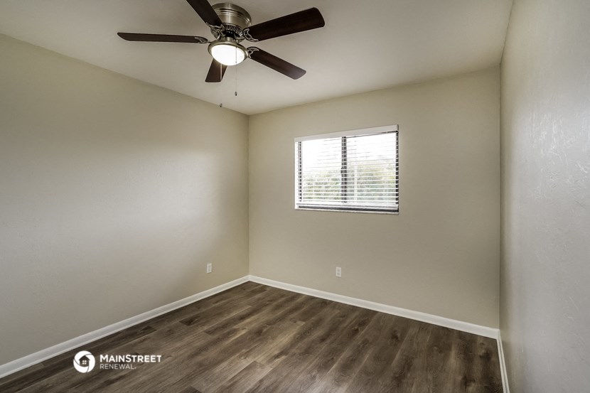 an empty room with a ceiling fan and a window