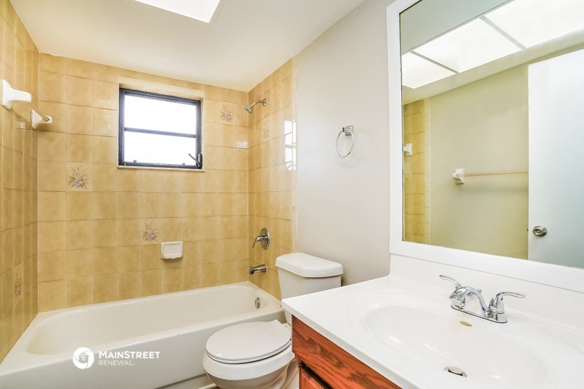 a bathroom with a tub sink and toilet and a mirror