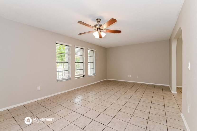 an empty living room with a ceiling fan and a tiled floor
