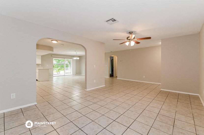 the spacious living room with tile flooring and a ceiling fan