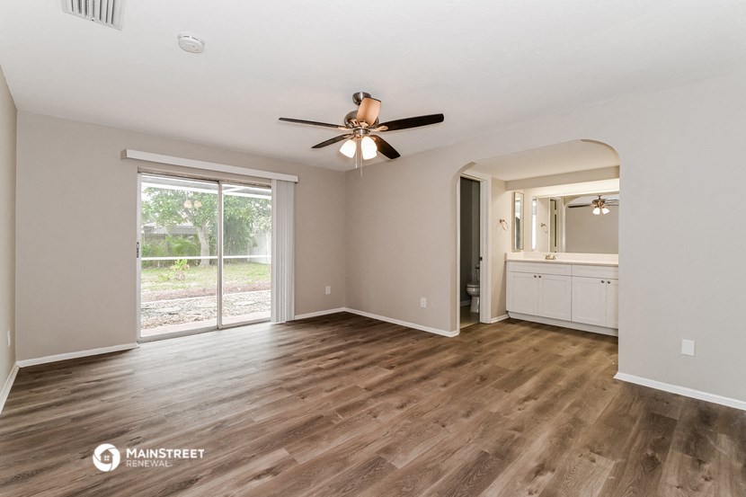 an empty living room with a ceiling fan and a window