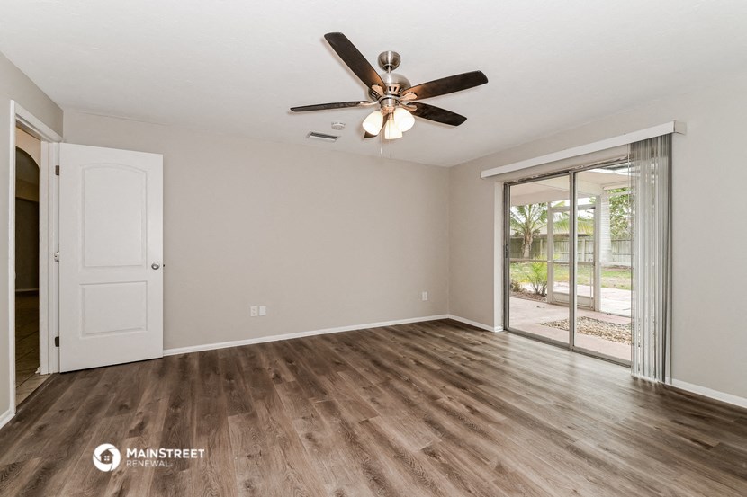 the living room of an empty house with a ceiling fan