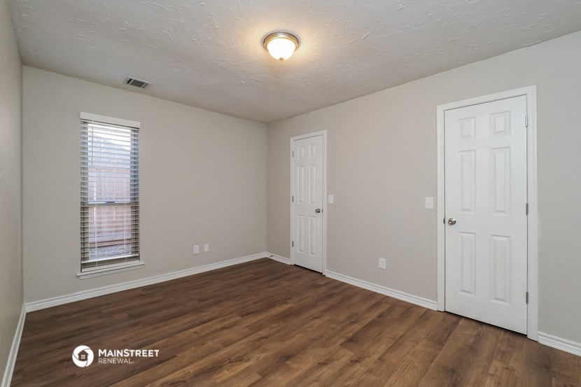 the interior of an empty room with wood flooring and a window