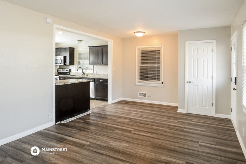 the living room and kitchen of an apartment with wood flooring