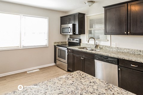 a kitchen with granite counter tops and black cabinets and stainless steel appliances
