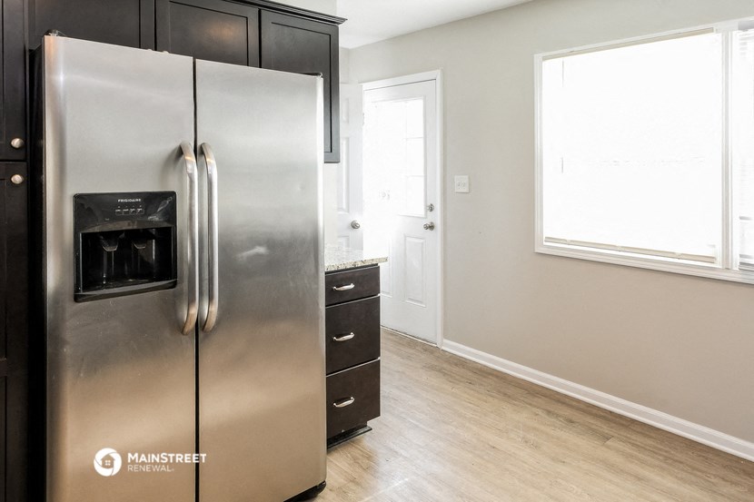 a kitchen with a stainless steel refrigerator and wooden floors