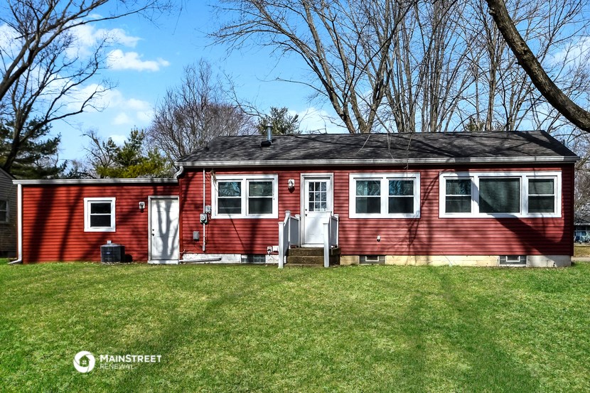 a red house with a black roof on top of a green lawn