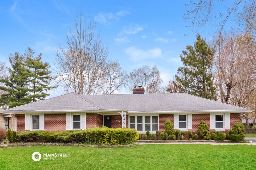 a red brick house with a green lawn and trees