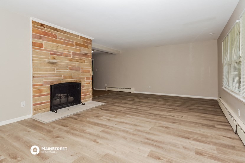 a living room with a brick fireplace and a wooden floor