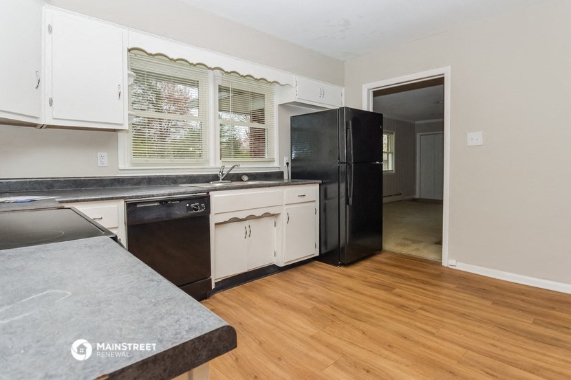 a kitchen with white cabinets and a black refrigerator