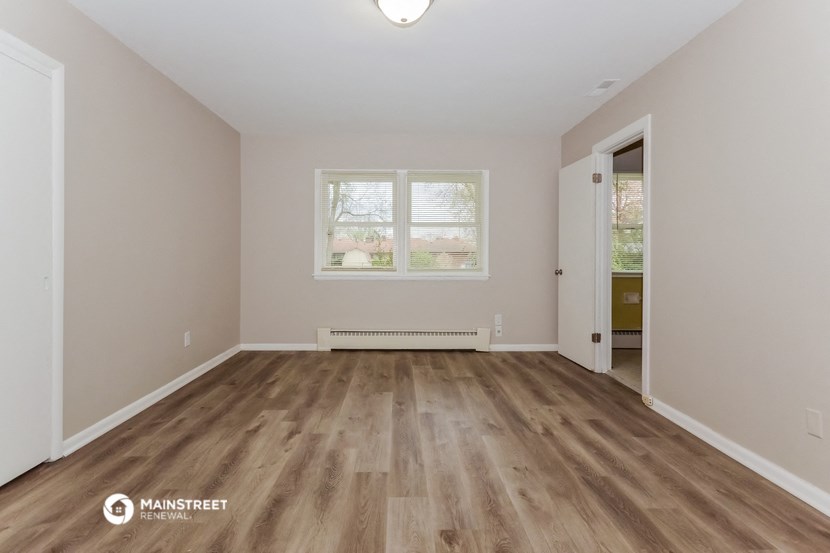 an empty living room with wooden floors and a window