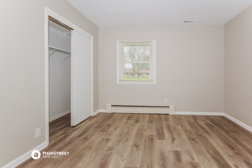 the living room of an empty house with wooden floors and a window