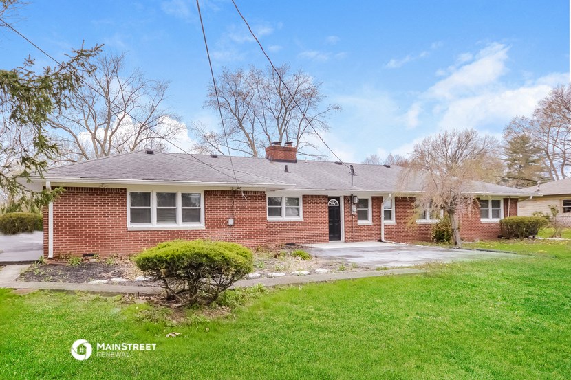 the front of a brick house with a yard and grass