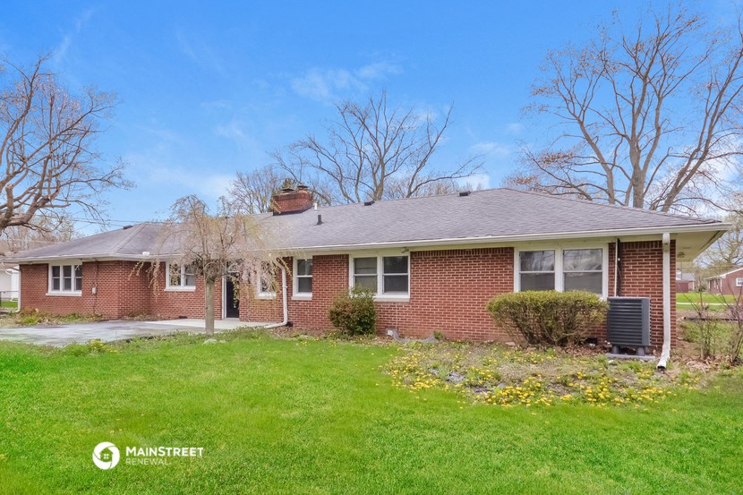 a brick house with a green lawn and a blue sky