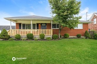 a red brick house with a porch and a green lawn