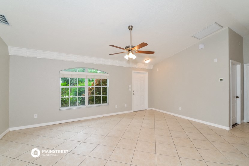 the empty living room of a house with a ceiling fan