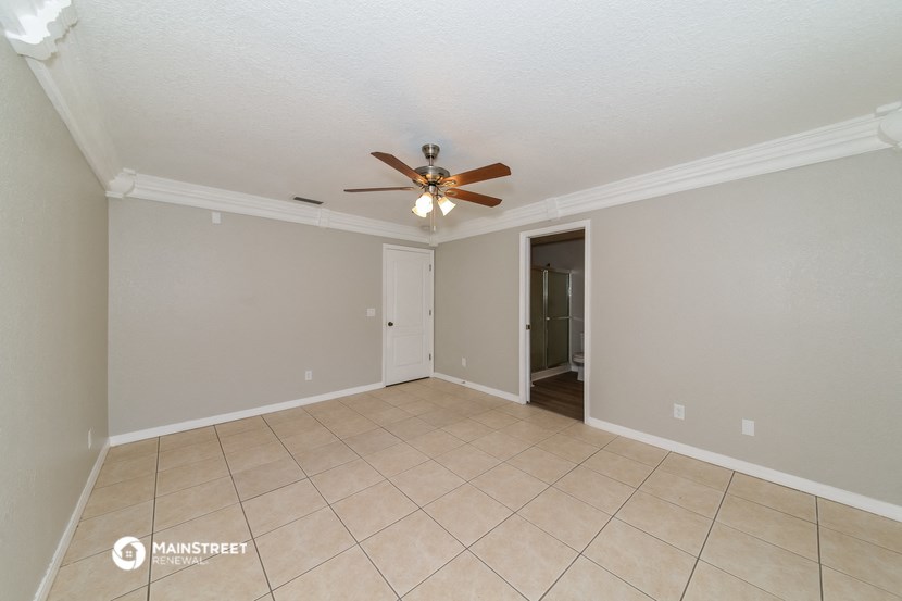 the spacious living room with ceiling fan and tile flooring