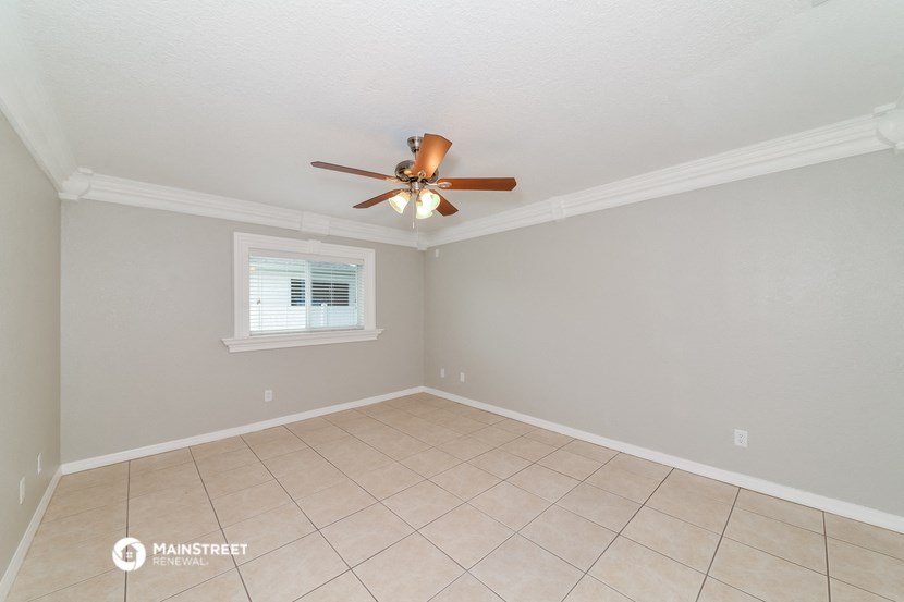 the spacious living room with ceiling fan and tiled floor