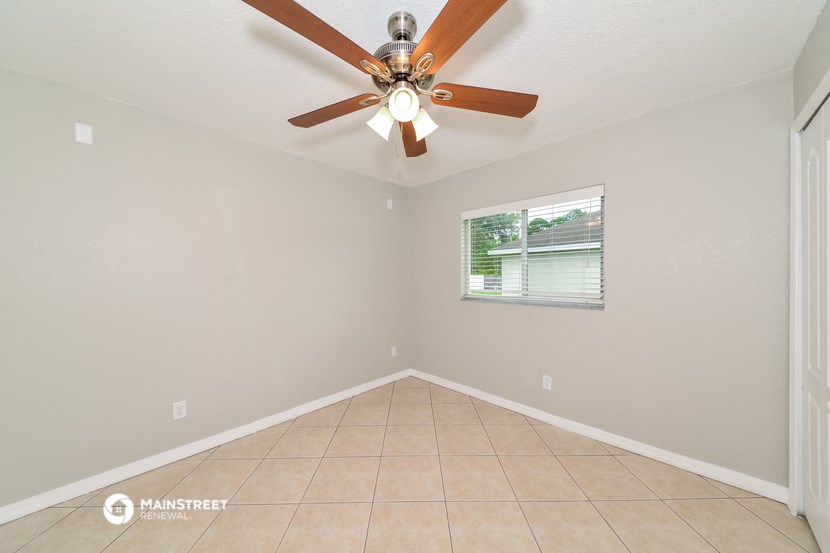the living room has a ceiling fan and a tiled floor