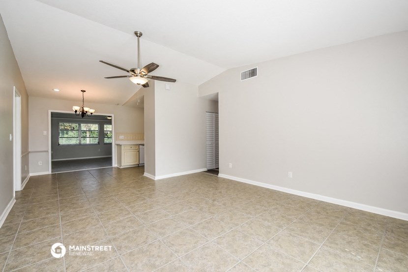 the spacious living room with tile flooring and ceiling fan